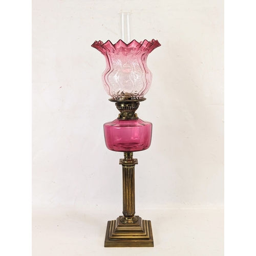 204 - A large Edwardian ruby glass brass oil lamp. With shade and funnel, 69cm