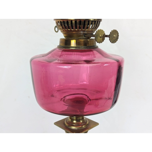 204 - A large Edwardian ruby glass brass oil lamp. With shade and funnel, 69cm