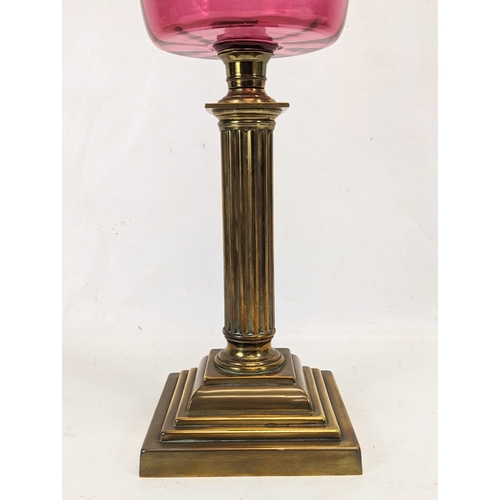 204 - A large Edwardian ruby glass brass oil lamp. With shade and funnel, 69cm