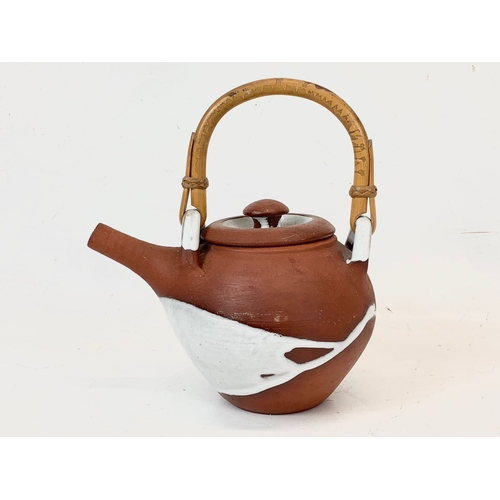 571 - A vintage glazed terracotta Japanese teapot with bamboo handle. 18 x 21cm