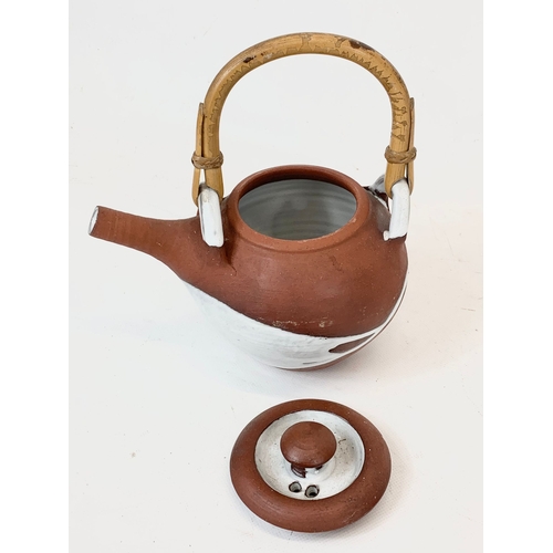 571 - A vintage glazed terracotta Japanese teapot with bamboo handle. 18 x 21cm