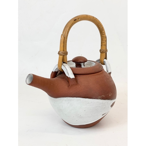 571 - A vintage glazed terracotta Japanese teapot with bamboo handle. 18 x 21cm