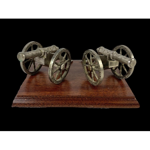 568A - A pair of silver plated cannons on a wooden plinth. 20.5 x 15.5 x 9cm.