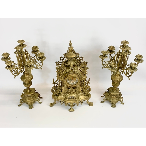 111 - A large 18th century style heavy brass clock set. Clock and a pair of candelabras. Clock measures 32... 