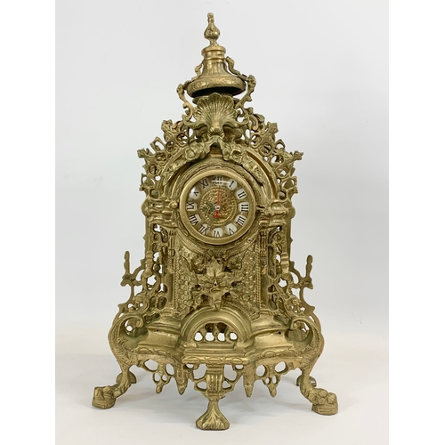 111 - A large 18th century style heavy brass clock set. Clock and a pair of candelabras. Clock measures 32... 