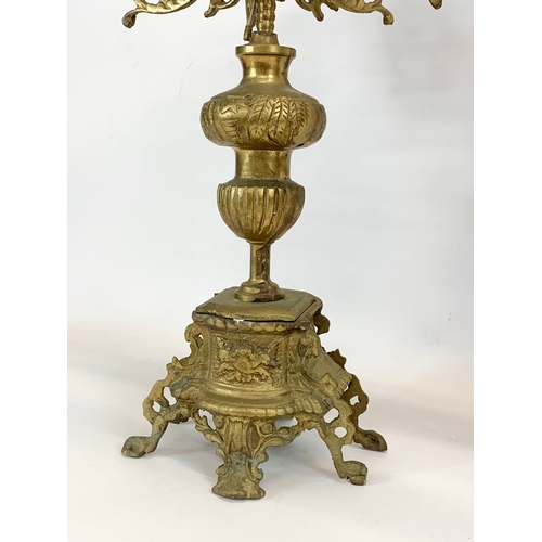 111 - A large 18th century style heavy brass clock set. Clock and a pair of candelabras. Clock measures 32... 