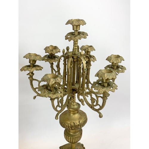 111 - A large 18th century style heavy brass clock set. Clock and a pair of candelabras. Clock measures 32... 