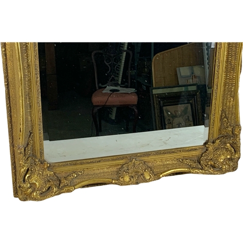 215 - A large ornate gilt framed mirror. Carvers and Gilders. 80 x 141.5cm