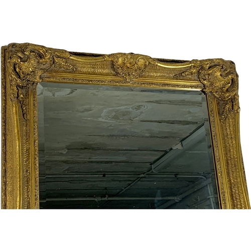 215 - A large ornate gilt framed mirror. Carvers and Gilders. 80 x 141.5cm