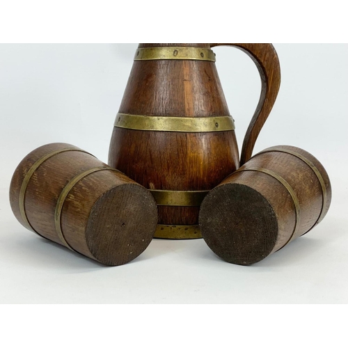 431 - An Edwardian oak brass bound 3 piece drinks set. Jug and 2 cups. Jug measures 23cm