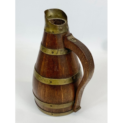 431 - An Edwardian oak brass bound 3 piece drinks set. Jug and 2 cups. Jug measures 23cm