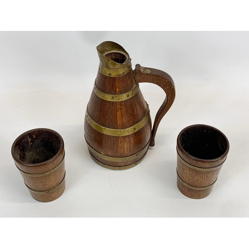 431 - An Edwardian oak brass bound 3 piece drinks set. Jug and 2 cups. Jug measures 23cm