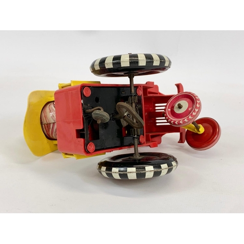 52 - A vintage windup tin plate Fireman in truck. 14 x 17cm.