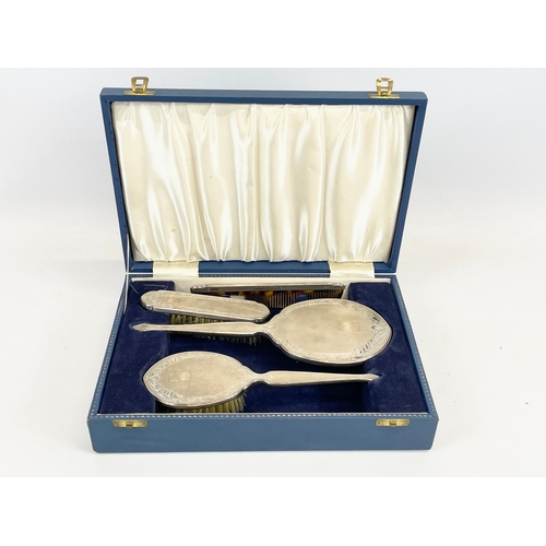 551 - A silver vanity set in case. 4 piece. Birmingham. Case measures 32 x 22 x 7cm