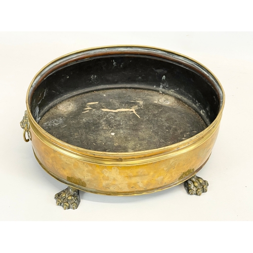 221 - An early 20th century brass coal bucket with paw feet and ring handles. 34 x 26 x 13cm