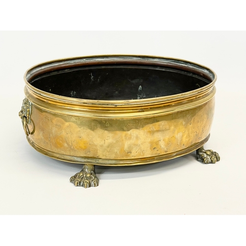 221 - An early 20th century brass coal bucket with paw feet and ring handles. 34 x 26 x 13cm