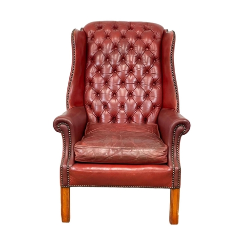 810 - A Georgian style deep button Ox-blood leather wingback armchair. 76 x 85