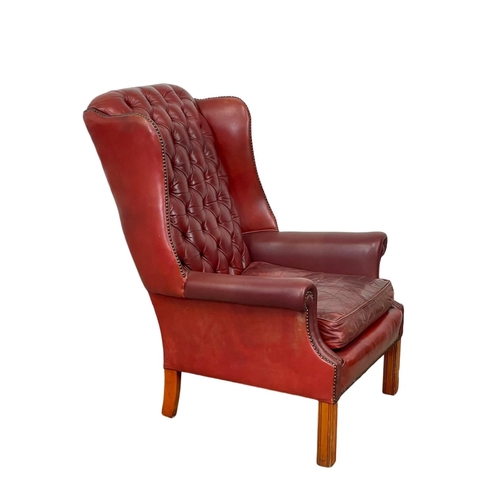 810 - A Georgian style deep button Ox-blood leather wingback armchair. 76 x 85