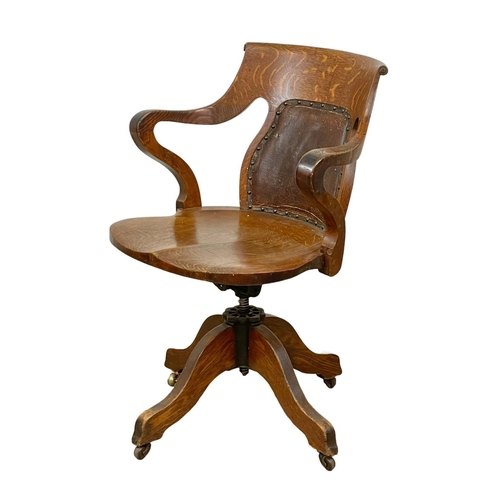 817 - A late Victorian / Edwardian oak swivel desk chair, from Hewetson, Milner & Thexton LTD London. Circ... 