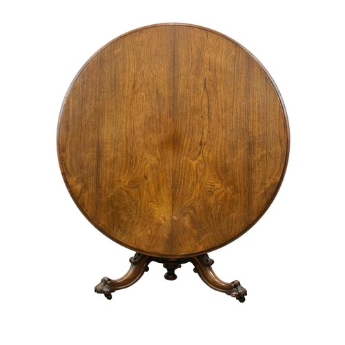 877 - A Victorian rosewood tilt top breakfast / dining table, on a carved pedestal base. 122 x 72cm