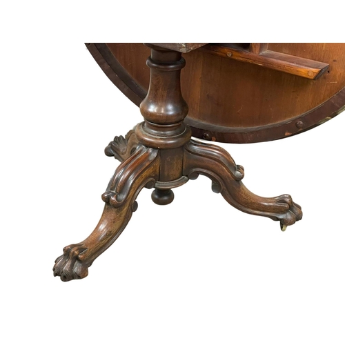 877 - A Victorian rosewood tilt top breakfast / dining table, on a carved pedestal base. 122 x 72cm