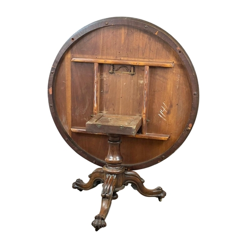 877 - A Victorian rosewood tilt top breakfast / dining table, on a carved pedestal base. 122 x 72cm