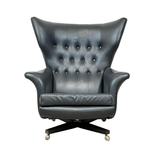 902 - A G-Plan “Blofeld” wingback swivel armchair in black vinyl and on a rosewood base. Model 6250R. 1962... 