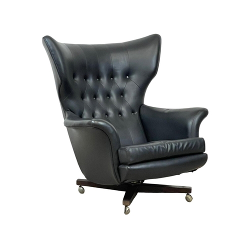 902 - A G-Plan “Blofeld” wingback swivel armchair in black vinyl and on a rosewood base. Model 6250R. 1962... 