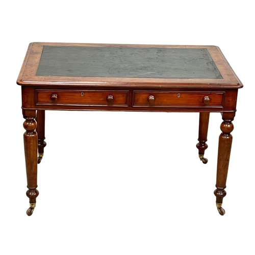 947 - A Victorian mahogany leather top writing table with 2 drawers and brass cup casters. 107 x 67 x 73cm