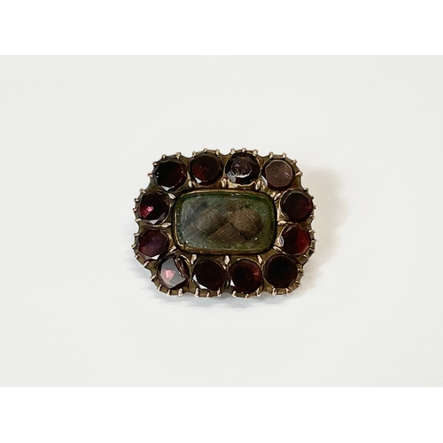 571 - A Victorian 9ct gold mourning brooch with garnet stones. 2.5cm