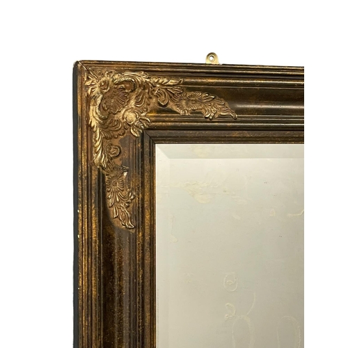 235F - A large ornate gilt framed bevelled mirror. 79x119cm