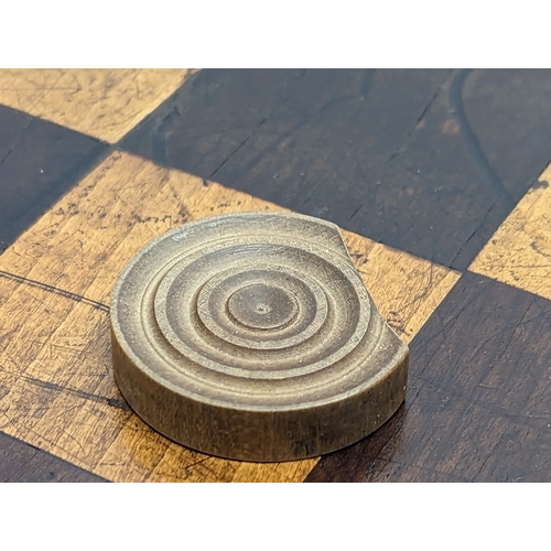 165 - An early 20th century mahogany draughts board with pieces. Board measures 51.5x45.5cm