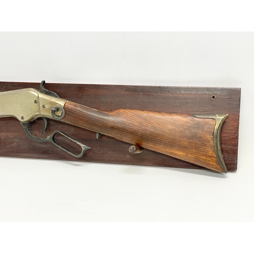 104 - A good quality replica Winchester rifle with wall mounted stand. Rifle measures 99.5cm