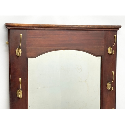 218 - An early 20th century mahogany hall mirror with brass coat hooks. 70x80.5cm