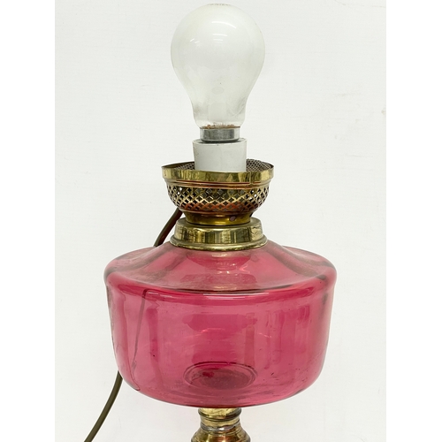 67 - A Victorian electrified oil lamp with Ruby Glass bowl and brass base. 40cm.