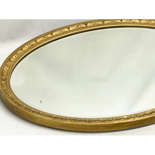 58 - An Edwardian ornate gilt framed oval mirror. 83x58cm