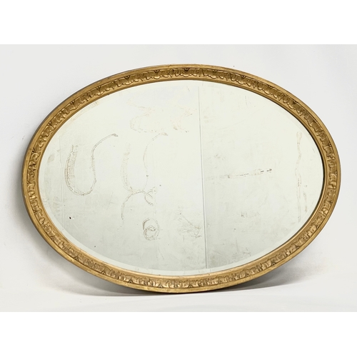 58 - An Edwardian ornate gilt framed oval mirror. 83x58cm