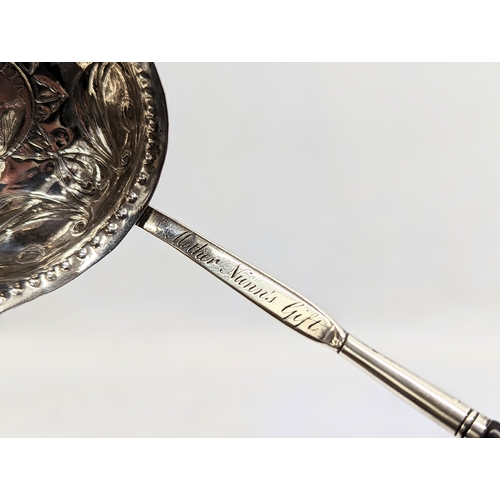 772 - A decorative silver Tottie spoon with coin image of Queen Anne with Balleen handle. 36cm