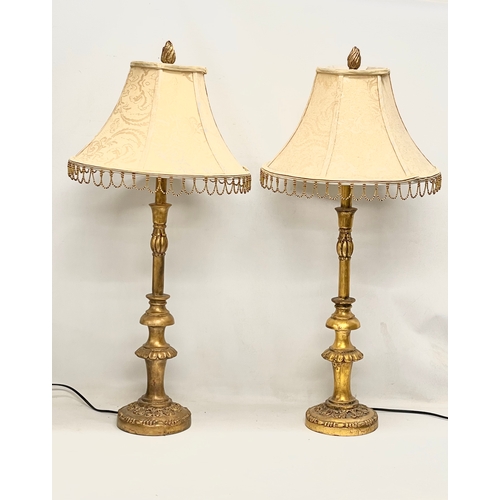 54 - A pair of tall ornate gilt table lamps. 85cm