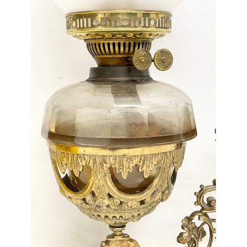 123 - A Victorian ornate brass wall handing double burner oil lamp with later shade. 36x54cm