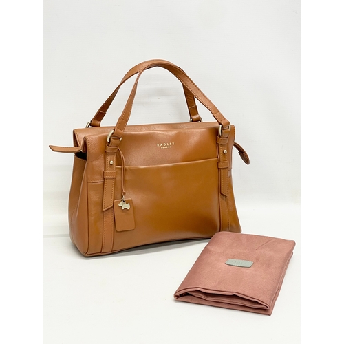 555 - A ladies leather handbag by Radley with cover.