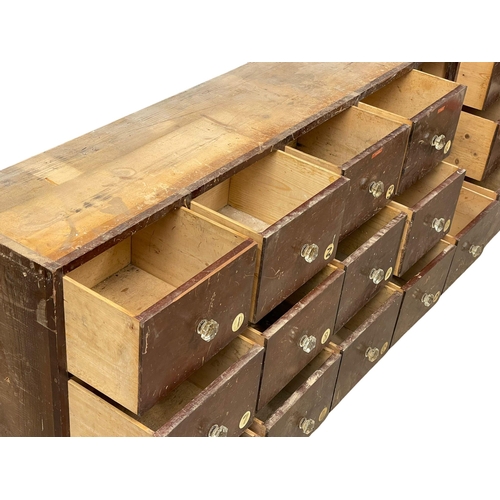 860 - A large Victorian pine apothecary shops bank of drawers with original glass handles. 196x31x69cm.