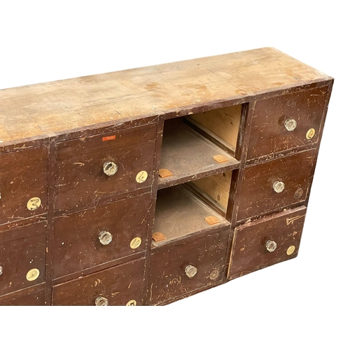 860 - A large Victorian pine apothecary shops bank of drawers with original glass handles. 196x31x69cm.