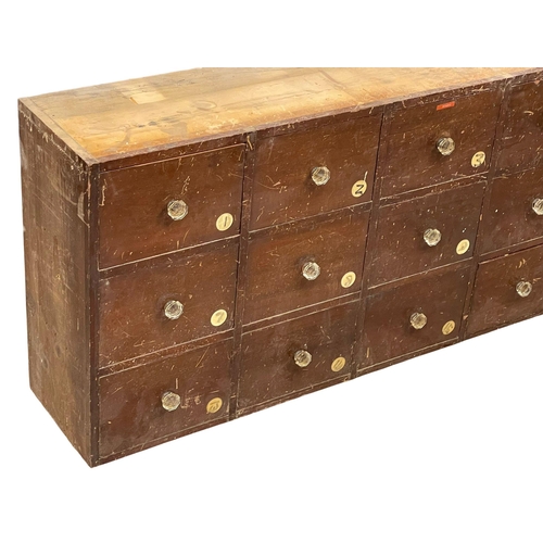 860 - A large Victorian pine apothecary shops bank of drawers with original glass handles. 196x31x69cm.