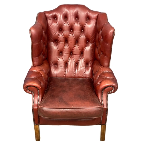 868 - A large Georgian style deep button ox-blood leather wingback armchair.