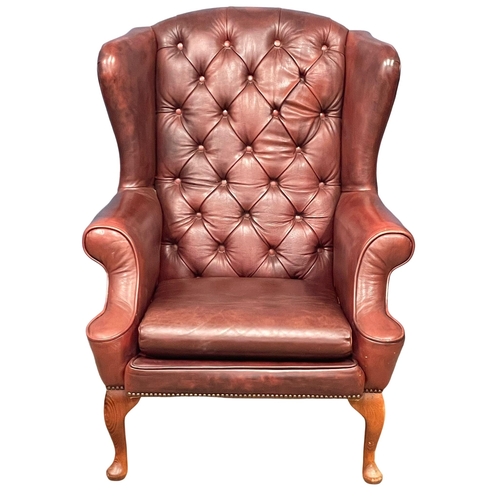 871 - A deep button ox-blood leather wingback armchair on Queen Anne legs.