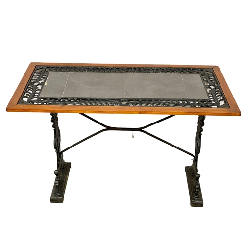 979 - A cast iron garden table with slate top. 116.5x61x70.5cm.