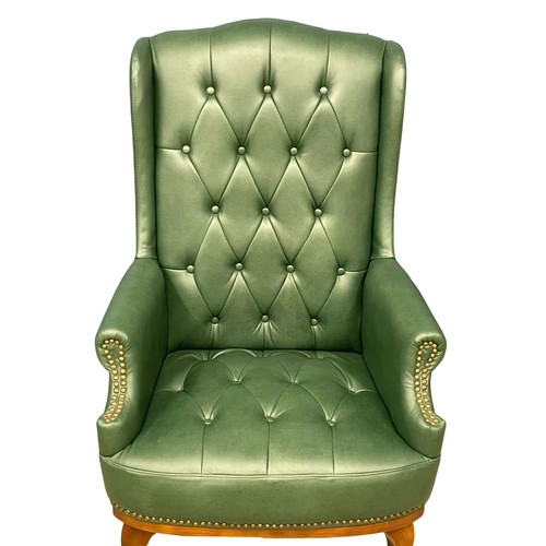 932 - A faux leather deep button wingback armchair.