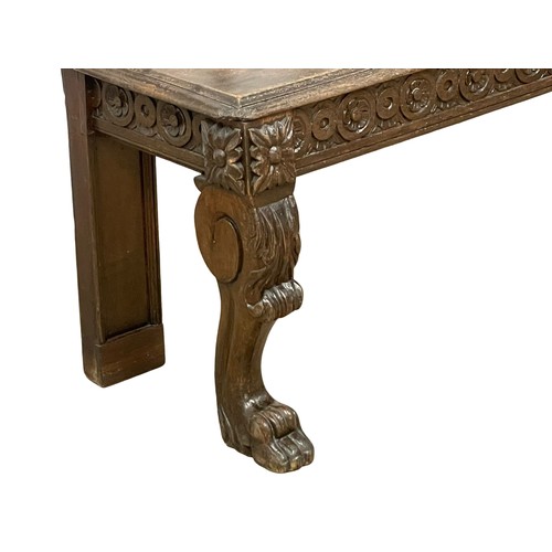 1033 - A Victorian carved oak hall bench on lion paw feet. Circa 1860. 123x40x94cm