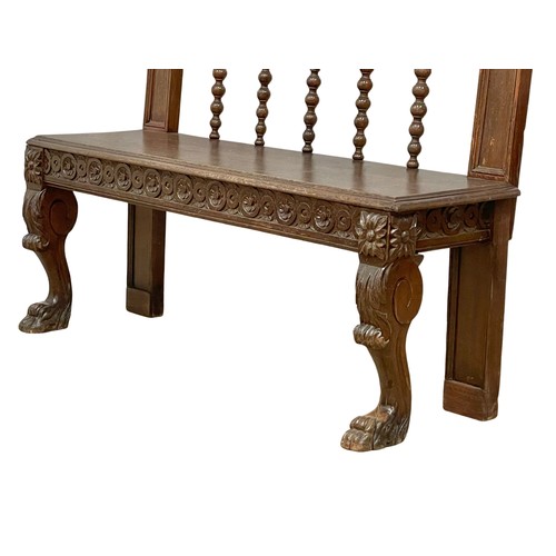 1033 - A Victorian carved oak hall bench on lion paw feet. Circa 1860. 123x40x94cm